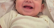 Josiah joined the competition — help win amazing prizes! baby, infant, child, smiling, laughing, portrait, face, close_up, indoor, blanket, bedding, white_clothing, onesie, happy, cozy, lying_down, head, eyes, mouth, photography