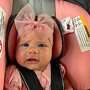 Delanis is registered to the contest to win money with this photo: baby, child, pink_bow, car_seat, safety_harness, pink_clothing, infant, cute, face, headband, sock, straps, seat, portrait, expression, indoors, child_safety, closeup, person, young