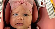 Delanis is registered to the contest to win money with this photo: baby, car_seat, child, child_safety, closeup, cute, expression, face, headband, indoors, infant, person, pink_bow, pink_clothing, portrait, safety_harness, seat, sock, straps, young