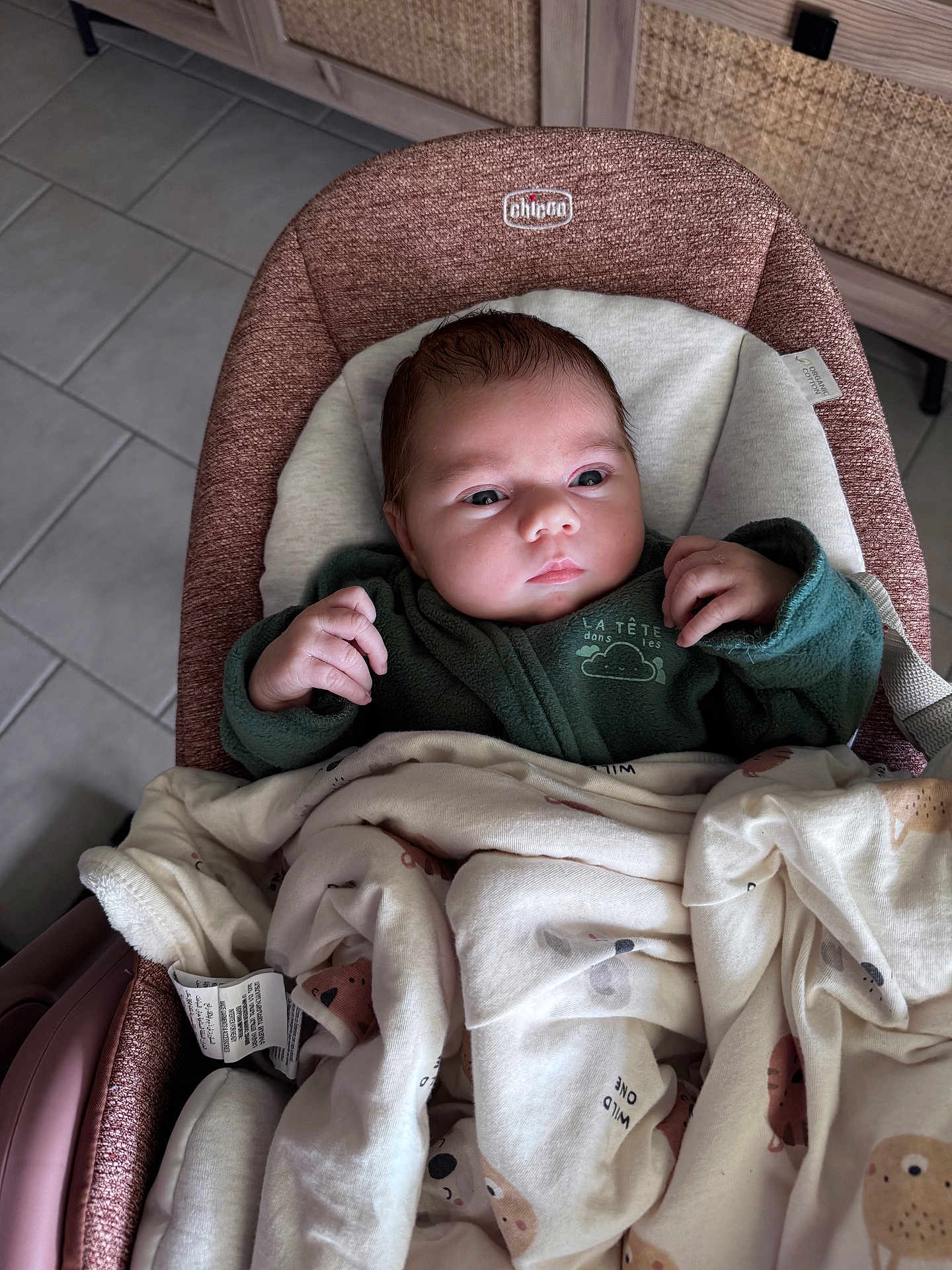 Esmée a rejoint le concours — aidez-le/la à gagner de superbes lots ! baby, infant, blanket, baby_chair, clothing, face, person, indoor, floor_tiles, curious, newborn, cute, warm, seated, soft_toys_pattern, baby_bedding, closeup, portrait, hands, head