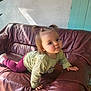 Lilith a rejoint le concours — aidez-le/la à gagner de superbes lots ! toddler, child, crawling, leather_couch, pigtails, indoors, curious, natural_light, wall, green_shirt, pink_pants, shoes, home, texture, shadow, hand, face, young_child, casual_clothing, expression
