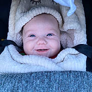 Prudence a rejoint le concours — aidez-le/la à gagner de superbes lots ! baby, smiling, blanket, cozy, infant, face, blue_eyes, soft_texture, warm_clothing, closeup, portrait, cute, child, happy, indoor, wrapped, car_seat, seatbelt, infant_clothing, comfort