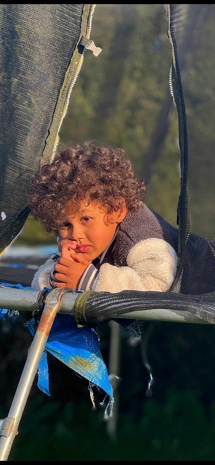 Kinsey a rejoint le concours — aidez-le/la à gagner de superbes lots ! blue_tarp, casual, child, curly_hair, daylight, expression, forest, jacket, leisure, metal_frame, nature, netting, outdoor, person, playground, portrait, texture, thoughtful, trampoline, young
