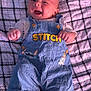 baby, smiling, overalls, clothing, infant, blanket, checkered_pattern, cute, happy, lying_down, child, portrait, face, small_hands, feet, indoor, casual, denim, button, young