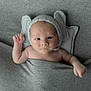 Mason is registered to the contest to win money with this photo: baby, infant, blanket, knitted_hat, cute, face, expression, small_hand, raised_fist, pillow, soft_texture, cozy, portrait, indoors, resting, child, newborn, headwear, sleeping_area, curious