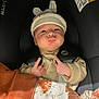 baby, car_seat, hat, bunny_ears, blanket, clothing, infant, face, child, seatbelt, cute, expression, indoor, person, newborn, pattern, warm, resting, sitting, cozy