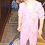 child, pajamas, pink, smiling, curly_hair, mop, broom, floor, tile_floor, kitchen, cleaning, standing, indoors, young_child, happy, person, footed_pajamas, toy, household, playful