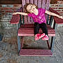 child, smiling, pink_shirt, black_pants, pink_shoes, wooden_chair, brick_wall, window, outdoor, concrete_floor, happy, girl, casual_clothing, relaxed_pose, playful, daylight, person, seated, portrait, fun