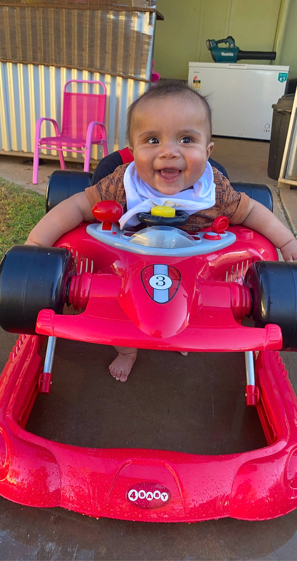 Heath is registered to the contest to win money with this photo: automotive_design, automotive_lighting, baby, baby_toddler_clothing, blue, chair, face, green, head, hood, joy, person, photograph, pink, red, riding_toy, smile, tire, toddler, vehicle