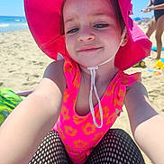 Harley joined the competition — help win amazing prizes! adult, baby, beach, clothing, coast, face, female, hat, head, nature, outdoors, person, photography, portrait, sea, shoreline, summer, sunhat, swimwear, water
