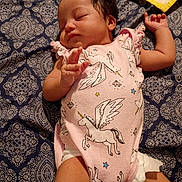 Musica is registered to the contest to win money with this photo: baby, sleeping, infant, onesie, unicorn, patterned_blanket, cute, peaceful, child, bedroom, soft_lighting, newborn, lying_down, pink_clothing, diaper, small_hand, face, hair, resting, indoors