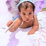 Jennifer is registered to the contest to win money with this photo: baby, child, infant, butterfly_costume, butterfly_wings, headband, antennae, crawling, bed, bedding, portrait, indoors, nursery, wide_eyed, curly_hair, smiling, pink, purple, costume, close_up