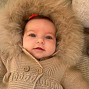 Vienna joined the competition — help win amazing prizes! baby, child, face, knitted_sweater, fur_hood, red_bow, blanket, cozy, cute, portrait, indoors, soft_texture, warm_clothing, infant, smiling, wide_eyes, headwear, buttoned_sweater, couch, relaxed