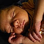 baby, sleeping, face, hand, infant, closeup, peaceful, skin, newborn, portrait, cute, resting, soft_light, yellow_clothing, dark_background, tiny_fingers, calm, indoors, child, relaxation