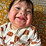 baby, child, smiling, face, onesie, bear_pattern, clothing, cheeks, happy, indoor, portrait, young_child, cute, infant, person, closeup, head, expression, sitting, background