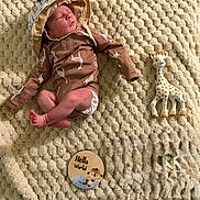 Julian joined the competition — help win amazing prizes! newborn, baby, sleeping, giraffe_pattern, hat, blanket, toy, giraffe_toy, wooden_disc, text, cozy, infant, cute, indoors, soft_texture, child, laying_down, peaceful, clothing, portrait