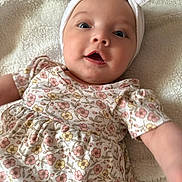 Keyonna-Lee is registered to the contest to win money with this photo: baby, infant, child, face, headband, bow, floral_dress, blanket, soft_texture, cute, smiling, reaching_out, pastel_colors, portrait, indoors, skin, hand, happy, closeup, lying_down