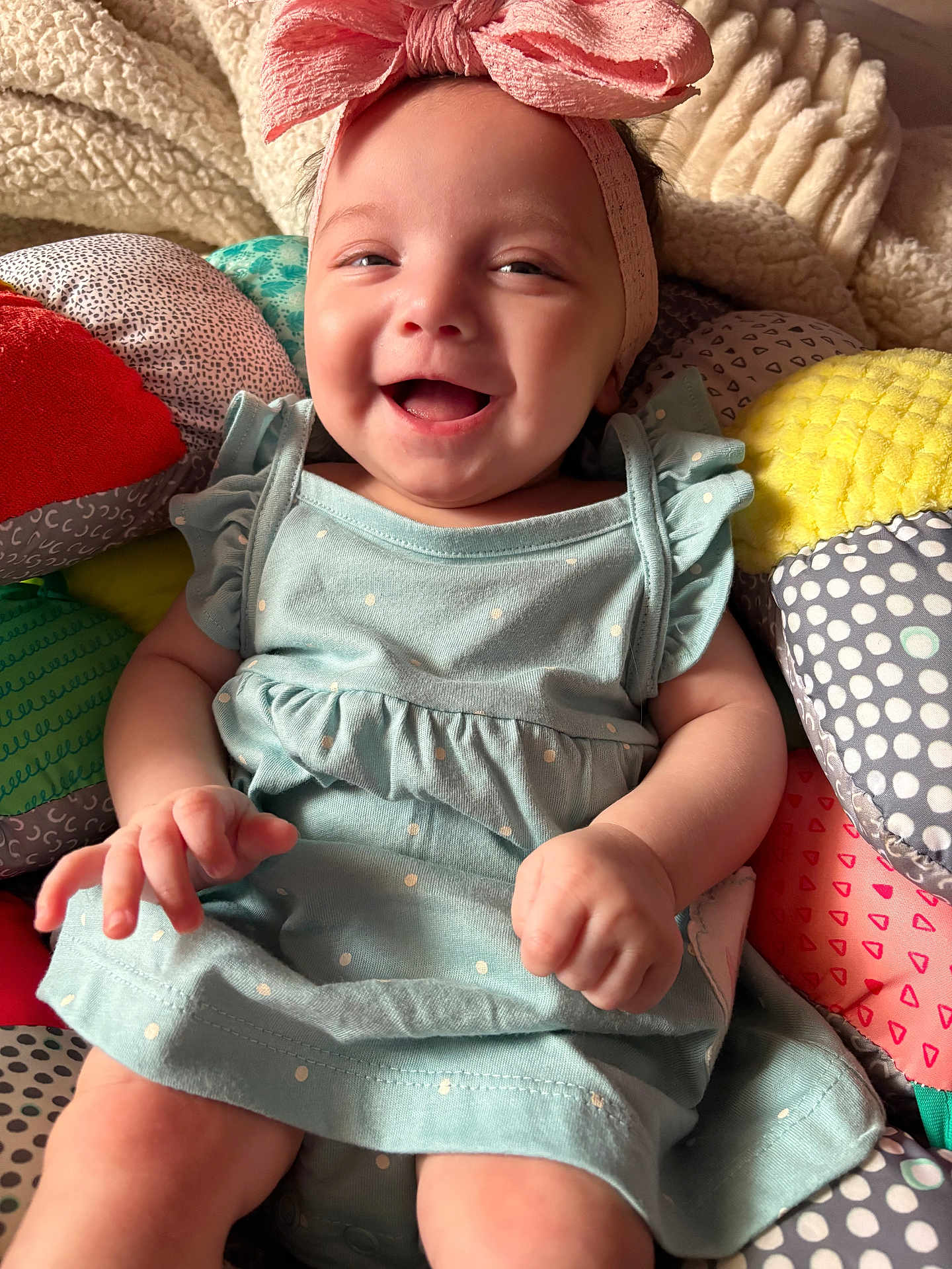 Keyonna-Lee is registered to the contest to win money with this photo: baby, smiling, headband, bow, dress, polka_dot, cushion, colorful, blanket, happy, infant, child, sitting, cute, portrait, indoor, soft, hands, face, cozy
