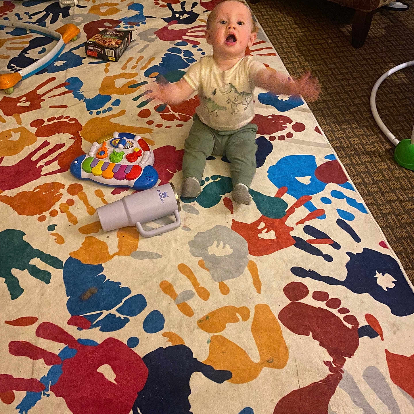 Daxton joined the competition — help win amazing prizes! baby, child, toy, colorful_rug, handprints, footprints, carpet, armchair, indoor, person, sitting, play, piano_toy, cup, floor, patterned_rug, furniture, reaching, happy, room