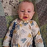 Daxton is registered to the contest to win money with this photo: baby, child, mickey_mouse, onesie, food, messy_face, quilt, patchwork, blue_eyes, infant, sleepwear, cute, hand, lying_down, fabric, pattern, comfort, indoors, portrait, young