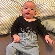 Ethan participe au concours pour gagner de l'argent avec cette photo : baby, barefoot, black_shirt, blue_pants, casual, child, clothing, cute, fabric, face, foot, hand, indoor, infant, lying_down, person, pillow, portrait, striped, young