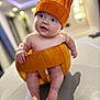 baby, pumpkin, hat, infant, cute, indoor, table, chubby_cheeks, knitted, orange, holiday, fall, child, legs, toes, smiling, costume, portrait, sitting, curious