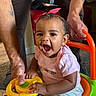 Dioř Aahmoř joined the competition — help win amazing prizes! baby, child, toy_car, steering_wheel, pink_bow, tattoo, adult_hand, indoor, carpet, clothing, smile, happy, person, play, seat, footwear, colorful, cute, expression, support