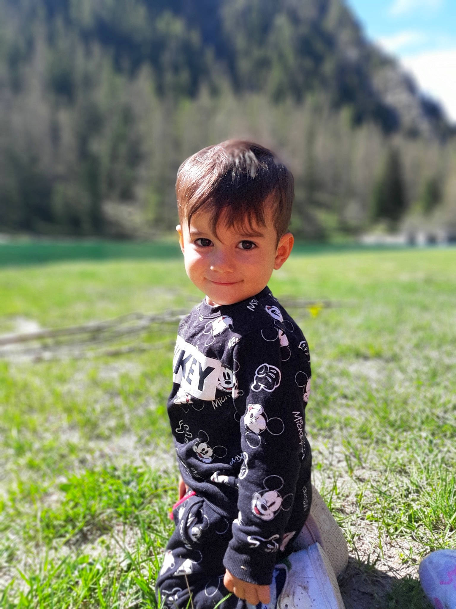 Sandro Mouries a rejoint le concours — aidez-le/la à gagner de superbes lots ! baby_toddler_clothing, black_hair, grass, grass_family, grassland, hairstyle, happy, landscape, lawn, leisure, meadow, mountain, outerwear, people_in_nature, person, plant, rural_area, sky, sleeve, toddler