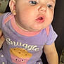 baby, infant, child, cute, purple_clothing, polka_dot_pants, snuggle_text, cupcake_graphic, earrings, chubby_cheeks, closeup, soft_lighting, indoor, person, portrait, young_child, curious, sitting, hand, face