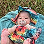 baby, infant, pacifier, colorful_clothing, hat, towel, grass, outdoor, feet, playful, cute, child, summer, toddler, nature, lying_down, skin, face, expressionless, barefoot