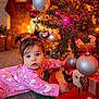 Alyara joined the competition — help win amazing prizes! baby, child, pajamas, pink_clothing, christmas_tree, ornaments, baubles, holiday_lights, stockings, carpet, indoor, festive, decorations, toddler, curious, face, eyes, hair, pigtails, gift_box