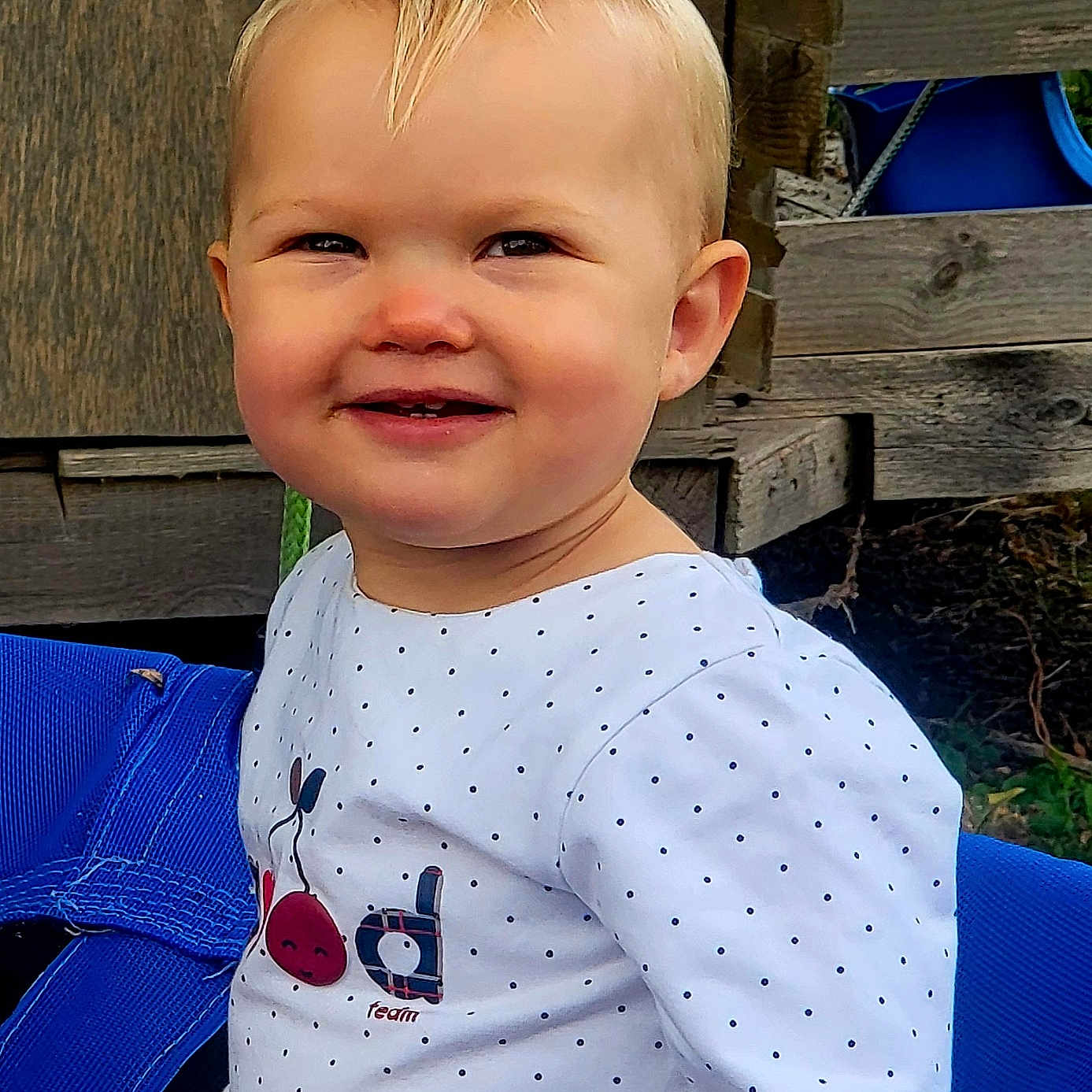 Armelle a rejoint le concours — aidez-le/la à gagner de superbes lots ! blue, casual_clothing, cherry_design, child, cute, daylight, face, happy, nature, outdoor, person, playground, polka_dot, portrait, sitting, smiling, swing, toddler, white_shirt, wooden_background