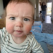 Daniel is registered to the contest to win money with this photo: baby, child, face, person, indoor, living_room, curious, expression, striped_shirt, drool, blurred_background, woman, walking, home, playpen, carpet, jeans, casual_clothing, furniture, light
