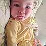 Ma'Kia Slapnicka is registered to the contest to win money with this photo: baby, child, infant, yellow_onesie, cushion, blanket, face, person, indoor, cute, expression, lying_down, soft_fabric, plush_toy, footwear, sleepwear, patterned_clothing, skin, head, eyes