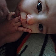 Ma'Kia Slapnicka is registered to the contest to win money with this photo: baby, closeup, face, hand, fingers, blanket, pattern, infant, child, skin, cute, expression, portrait, young, eyes, soft, indoors, person, sleepy, warm