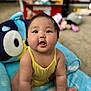 baby, child, crawling, yellow_clothing, plush_toy, indoor, playmat, cute, curious, soft, carpet, toy, person, young_child, infant, chubby_cheeks, smiling, bright, comfortable, home