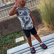 Asiyah Sareal is registered to the contest to win money with this photo: child, bench, outdoor, urban, grass, buildings, clouds, sky, concrete, person, shorts, tank_top, footwear, socks, hand_gesture, playful, standing, nature, daytime, expression
