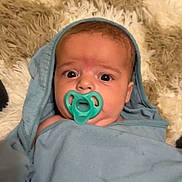 Dawson joined the competition — help win amazing prizes! baby, pacifier, blanket, hood, infant, face, eyes, expression, curious, lying_down, soft_texture, rug, blue, teal, child, newborn, wrapped, indoors, portrait, cute