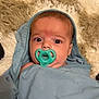 baby, pacifier, blanket, hood, infant, face, eyes, expression, curious, lying_down, soft_texture, rug, blue, teal, child, newborn, wrapped, indoors, portrait, cute