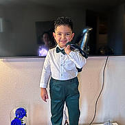 Ian David joined the competition — help win amazing prizes! child, boy, smiling, suit, bow_tie, white_shirt, green_trousers, standing, indoor, portrait, television, reflection, balloon, decorative_rose_under_glass, socks, jacket, hairstyle_spiky, home_decor, table, wall