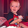 Lucas is registered to the contest to win money with this photo: toddler, child, red_eye, bed, blanket, indoor, curtain, clothing, holding_object, light, room, wall, face, person, toy, furniture, comfort, sleepwear, young_child, casual