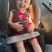 Lucas is registered to the contest to win money with this photo: toddler, car_seat, child, smiling, sunlight, vehicle_interior, seatbelt, red_clothing, safety, happy, indoors, travel, seat, window, daylight, young_child, person, cute, baby, car