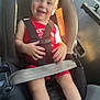 toddler, car_seat, child, smiling, sunlight, vehicle_interior, seatbelt, red_clothing, safety, happy, indoors, travel, seat, window, daylight, young_child, person, cute, baby, car