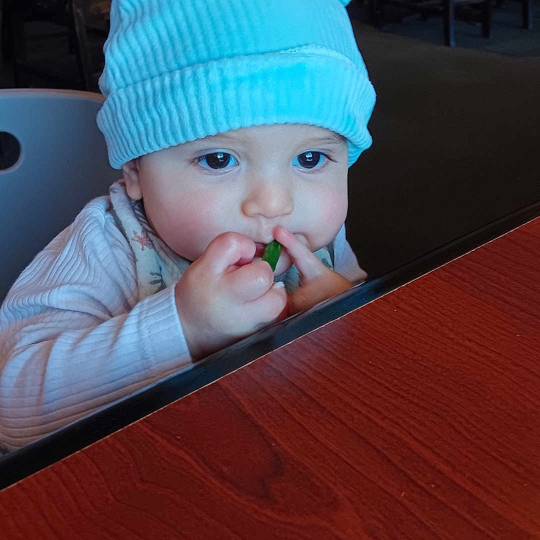 Mathias Sandoval is registered to the contest to win money with this photo: adult, baby, beanie, bodypart, cap, clothing, face, finger, hand, hardwood, hat, head, indoors, male, man, person, photography, portrait, restaurant, wood