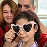 family, child, woman, man, indoor, portrait, sunglasses, heart_shaped_glasses, smile, red_clothing, purple_dress, headband, window, blinds, closeup, people, casual, happy, together, fun