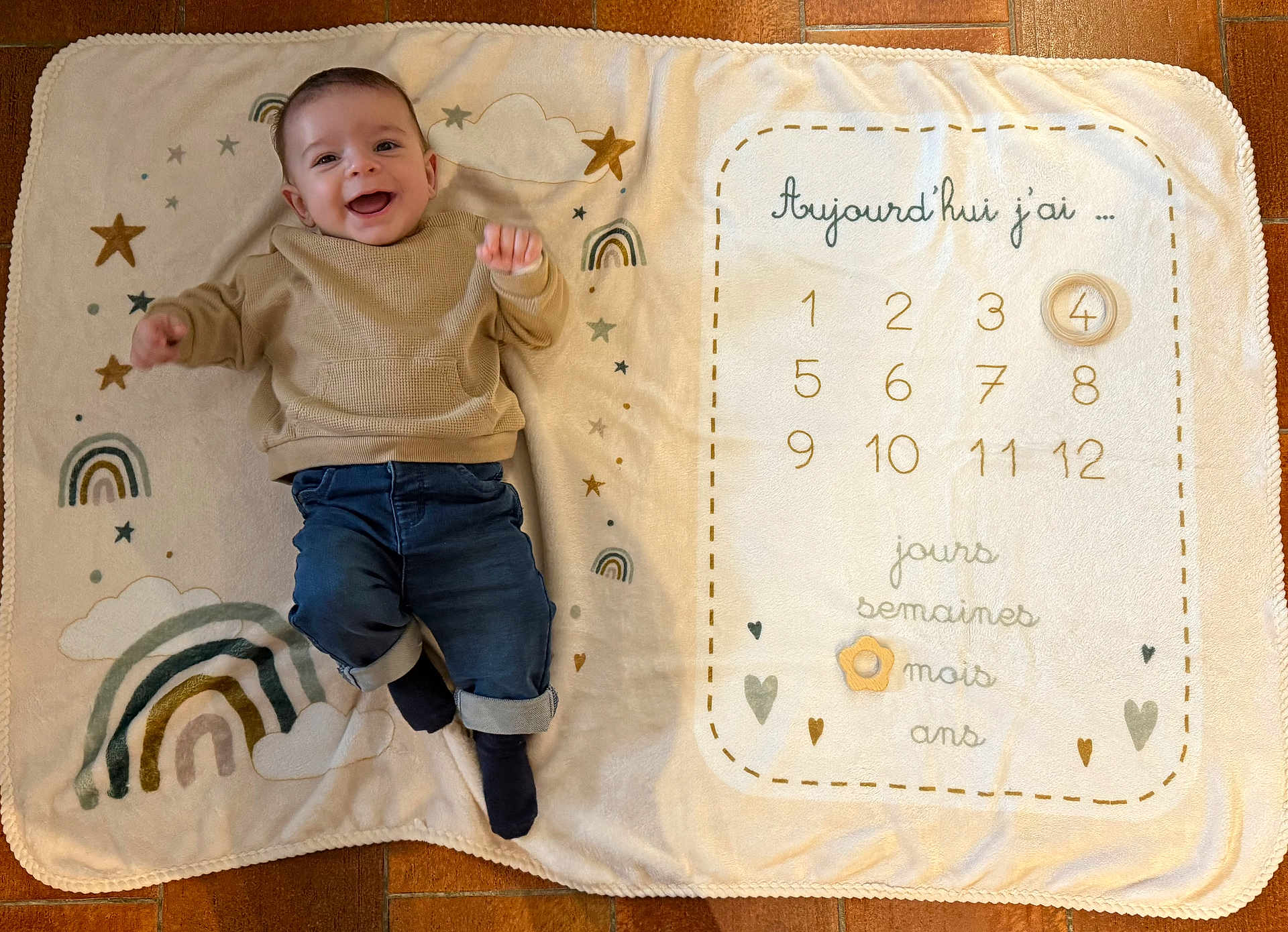 Leny participe au concours pour gagner de l'argent avec cette photo : baby, blanket, smiling, infant, clothing, jeans, sweater, rainbow, stars, floor, milestone, age_tracker, happy, cute, lying_down, child, indoors, playful, soft_texture, portrait