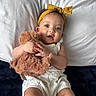 baby, child, infant, toddler, portrait, smiling, happy, bed, bedding, pillow, teddy_bear, stuffed_animal, headband, bow, white_outfit, indoor, bedroom, lying_down, hands, cuteness