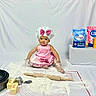 baby, child, chef_hat, pink_apron, bow, polka_dots, flour, baking, rolling_pin, butter, flour_bag, baking_soda, kitchen, baking_supplies, sitting, smiling, portrait, indoor, food_preparation, playful