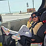 Esah Mariyam is registered to the contest to win money with this photo: child, car_seat, sunglasses, rainbow_sneakers, car_interior, road, ocean_view, window, seatbelt, yellow_top, leggings, child_safety, casual, relaxing, sunlight, road_sign, bottle, cool_kid, travel, daytime