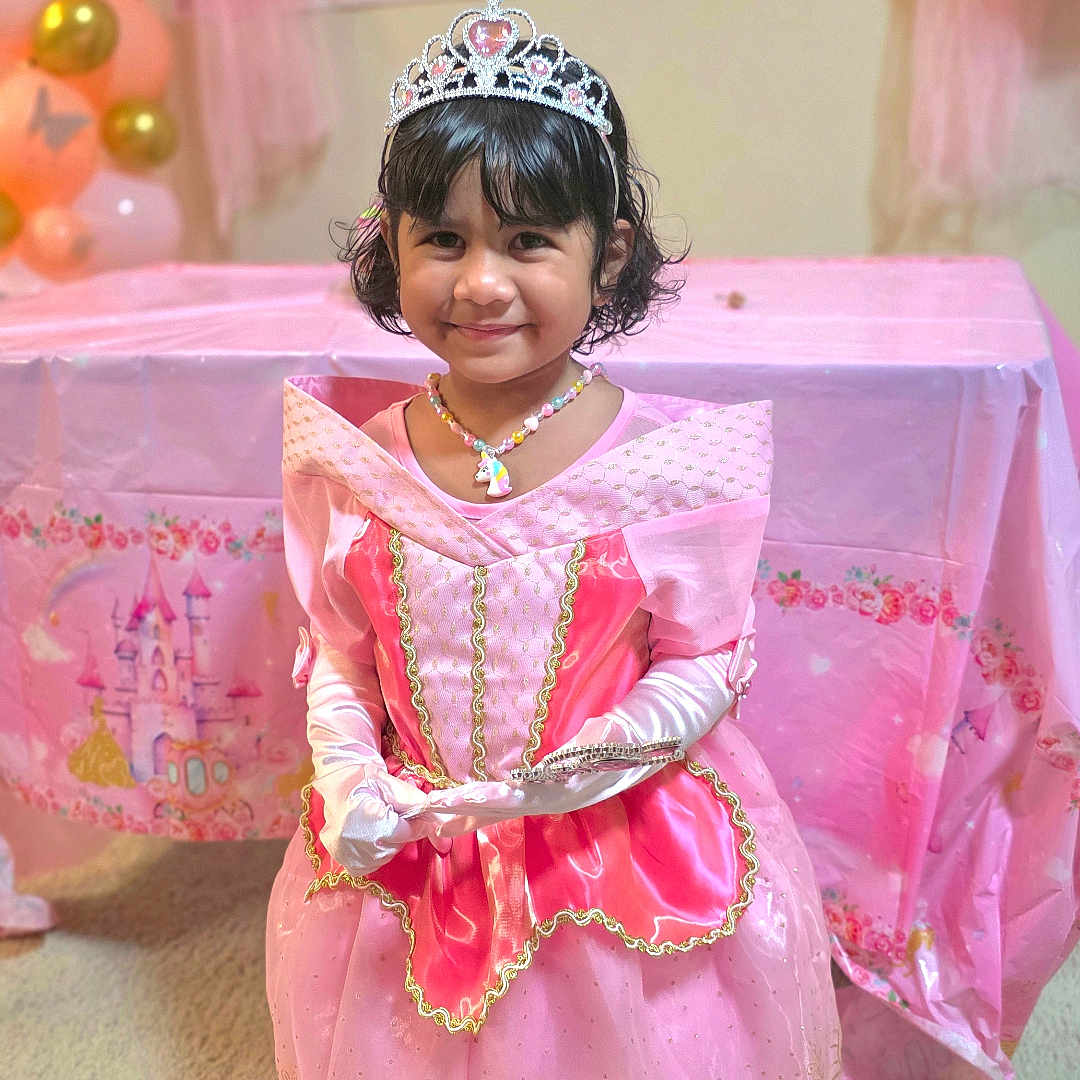 Esah Mariyam is registered to the contest to win money with this photo: child, girl, birthday_party, princess_costume, tiara, pink_dress, gloves, necklace, balloons, party_decoration, banner, smile, indoor, carpet, table, celebration, festive, young_child, cute, portrait